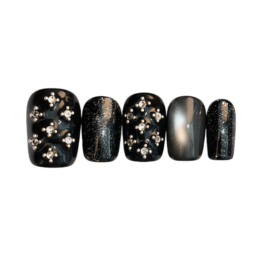 Set of five black nail art designs with gold and silver decorations on a white background