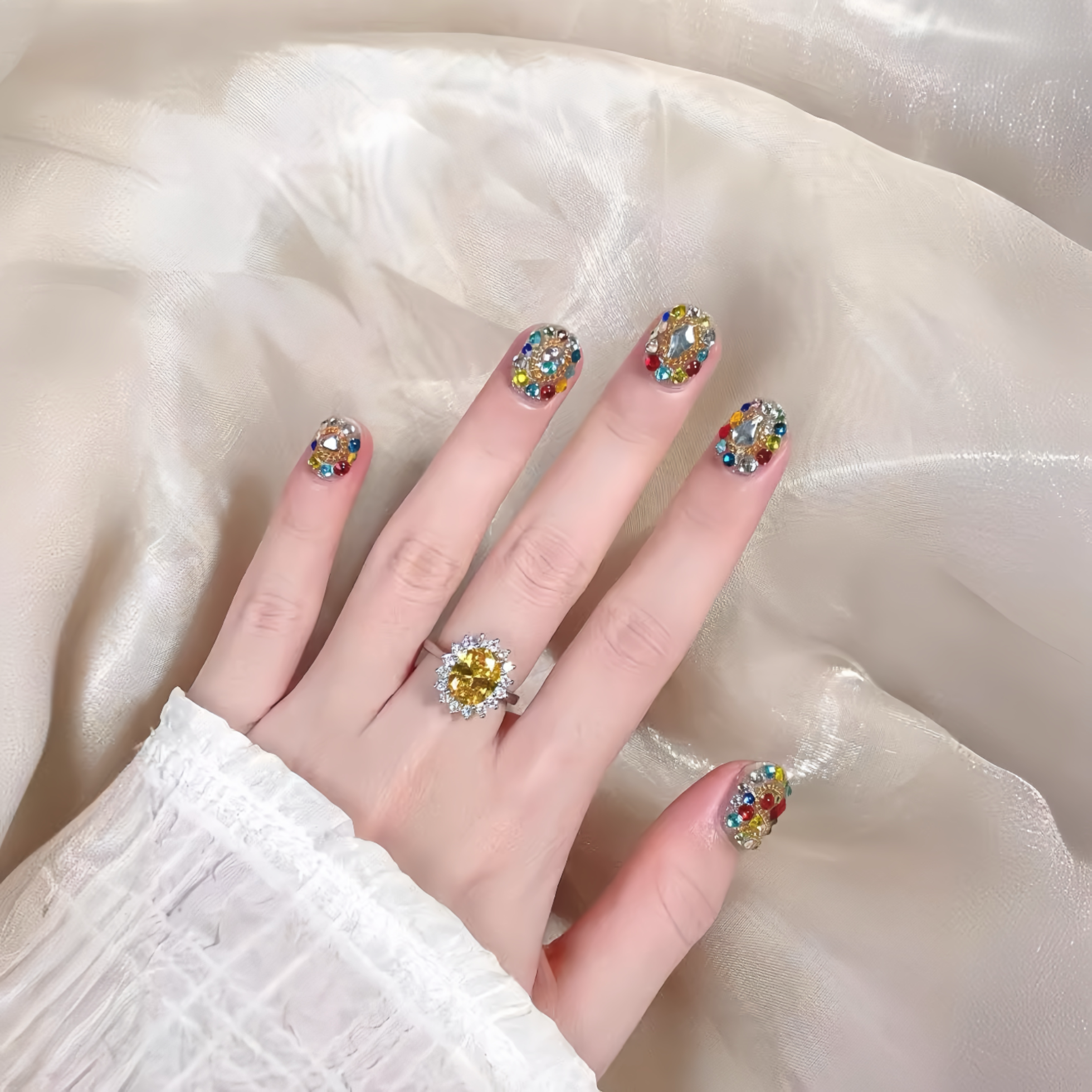 Hand wearing colorful gemstone rings on a soft fabric background
