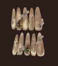 Decorative false nails with crystals and gold accents on a dark background