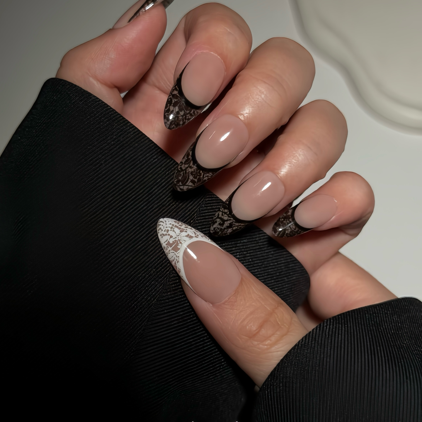 Close-up of a hand with stylish nail designs on a neutral background