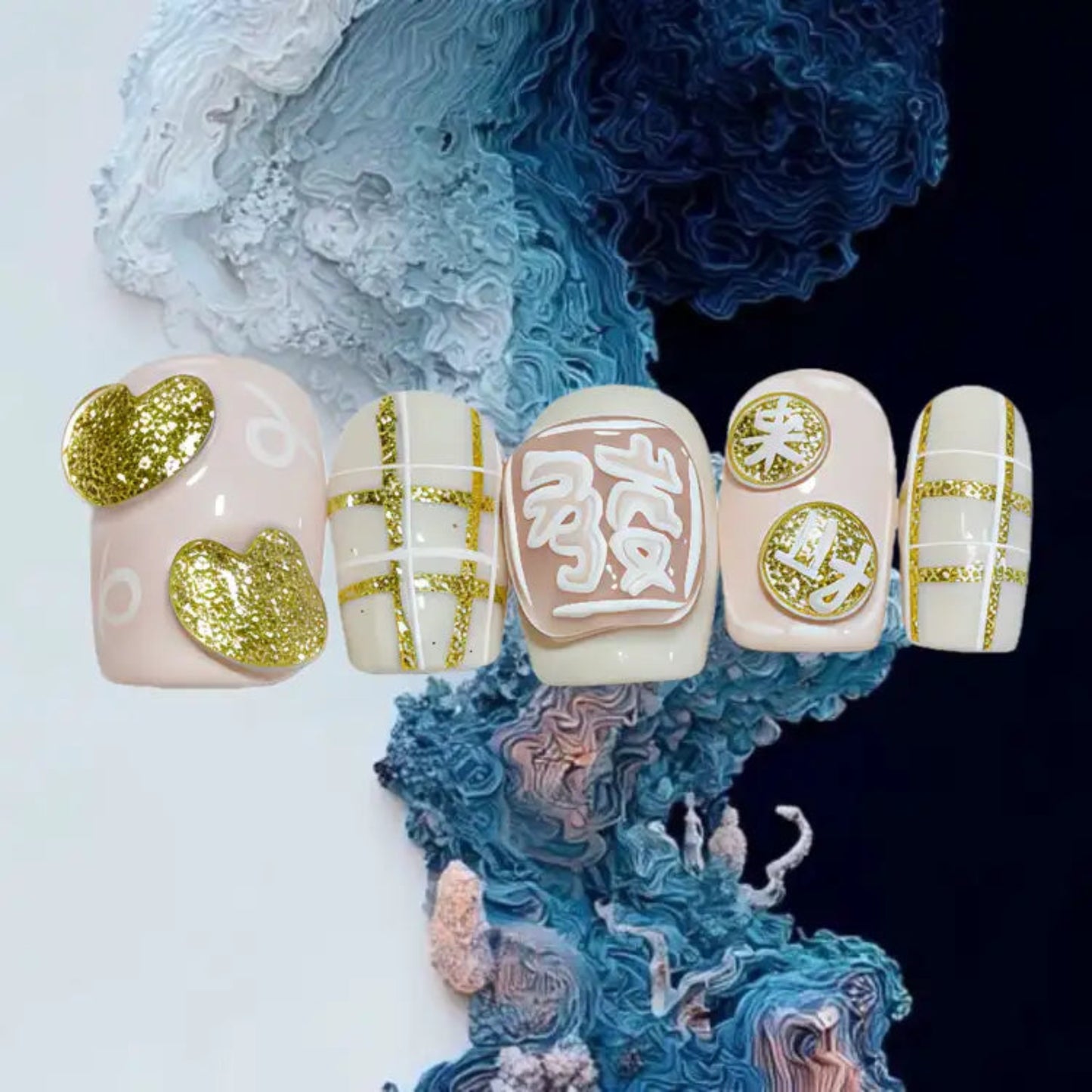 Decorative false nails with gold and white designs on a textured blue and white background