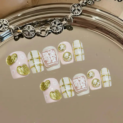 Decorative false nails with gold and white designs on a reflective surface.