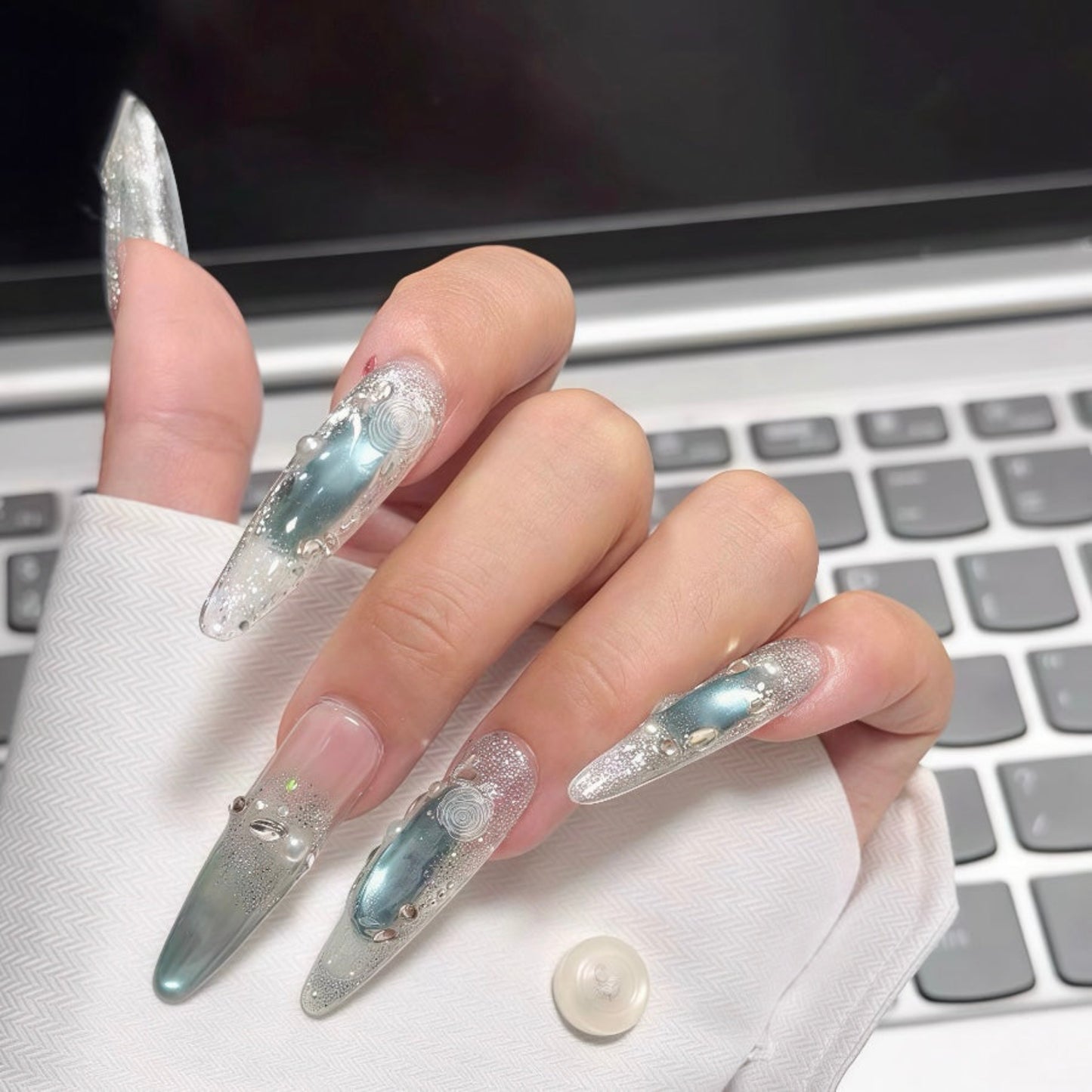 Hand with decorative nails in front of a laptop