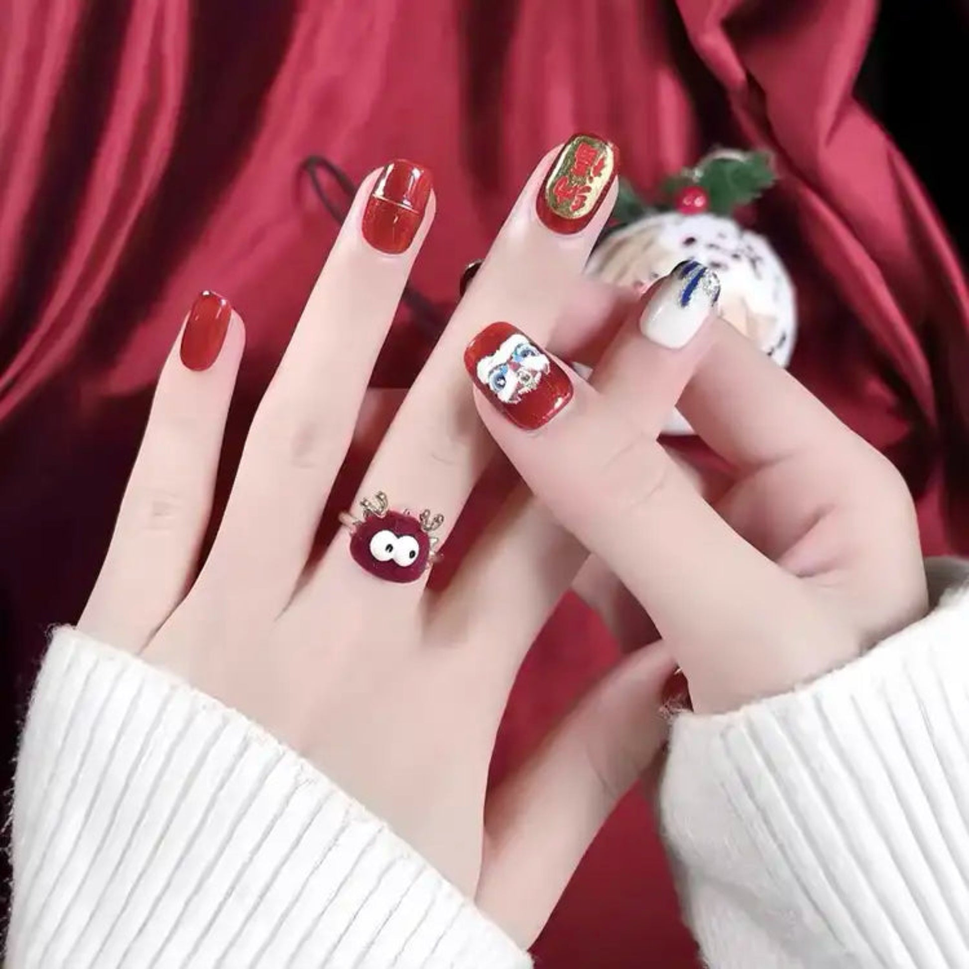 Close-up of hands with red nail polish and decorative designs against a red background