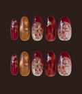 Set of red and gold nail designs with floral embellishments on a dark background