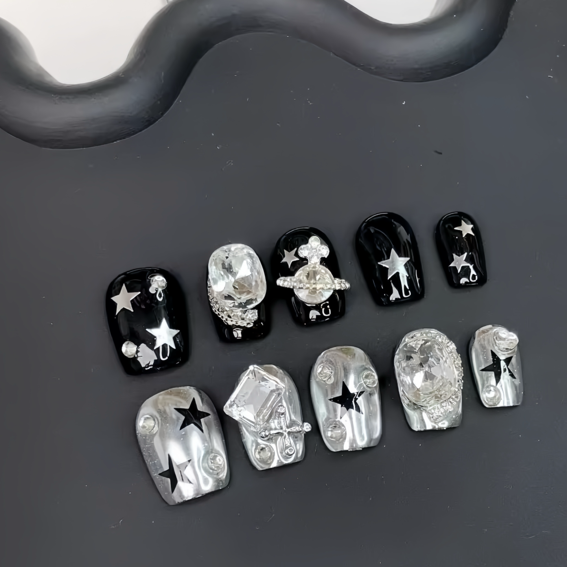 Set of black and silver nail art decorations on a dark surface