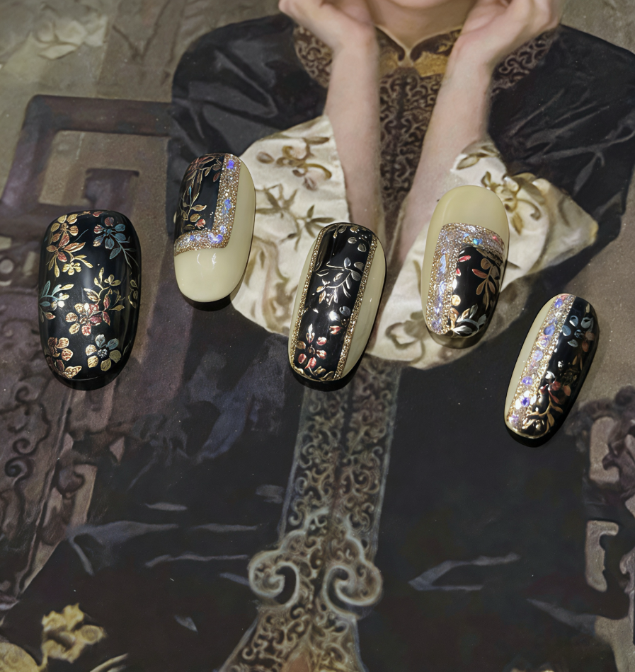 Decorative nail art on a person's hand with intricate designs.