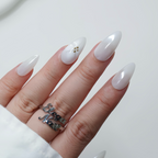 Hand with long white nails and a silver ring on a light background