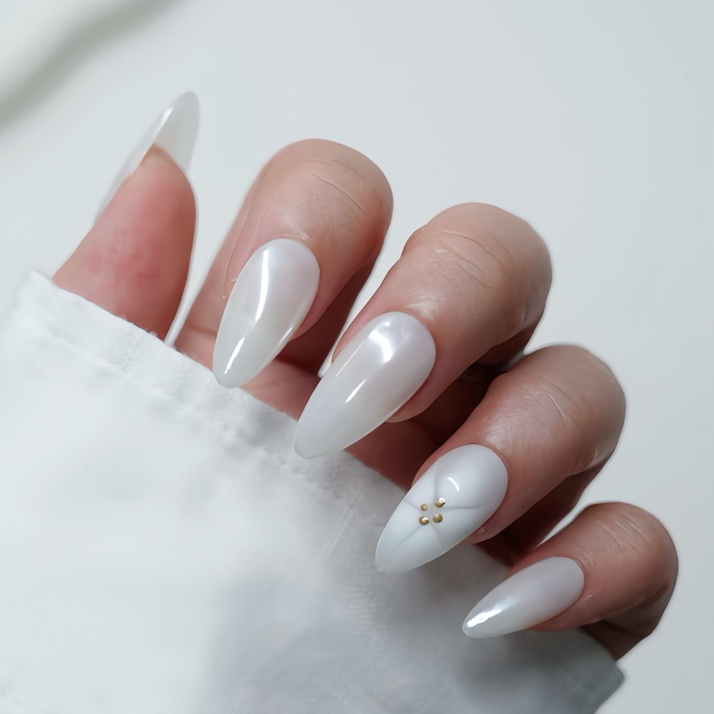 Hand with white nail polish on a plain background