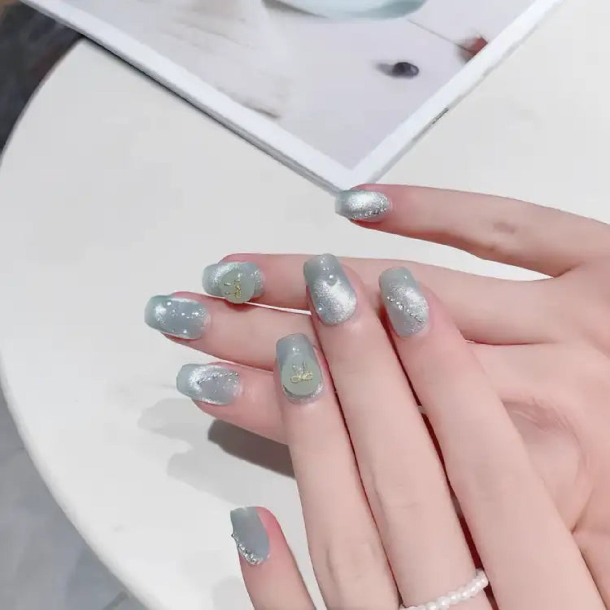 Hand with silver glittery nail polish on a white background