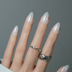 Hand with beige nail polish and silver rings on a gray background