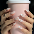Hand with manicured nails holding a pink cup against a dark background