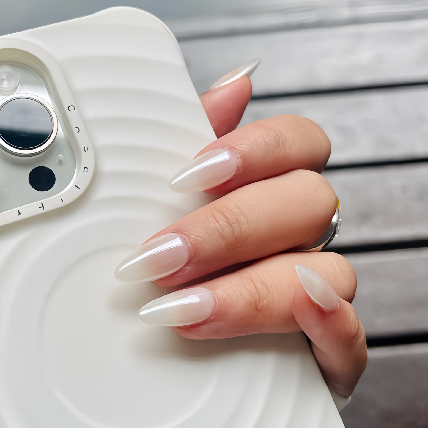 Hand with long, manicured nails holding a white phone case.