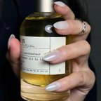 Hand holding a bottle with a label, against a dark background