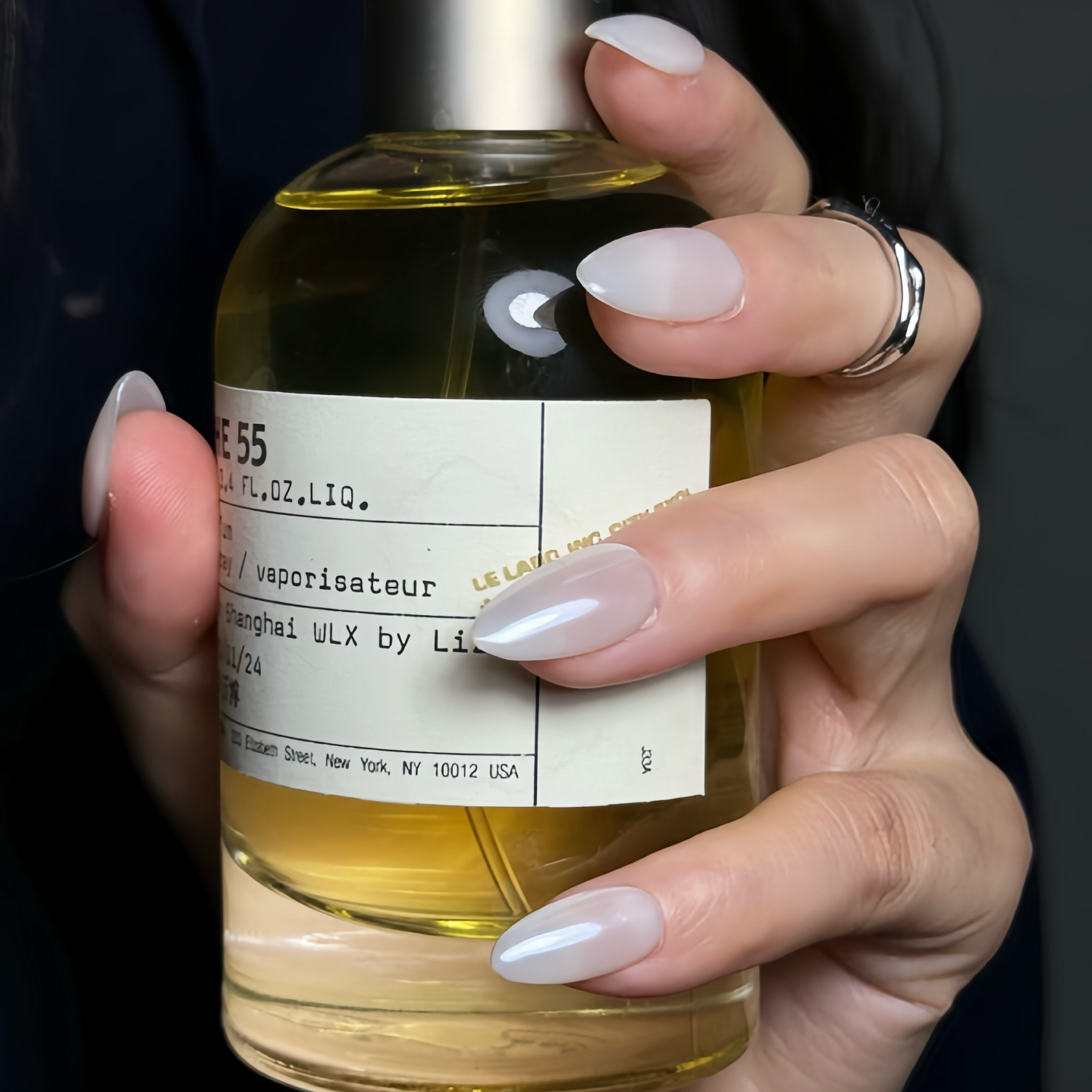 Hand holding a bottle with a label, against a dark background
