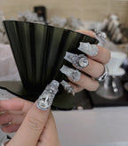 Close-up of a hand with intricately designed silver rings on a blurred background