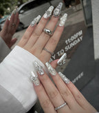 Close-up of a hand with ornate nail art and jewelry against a blurred background