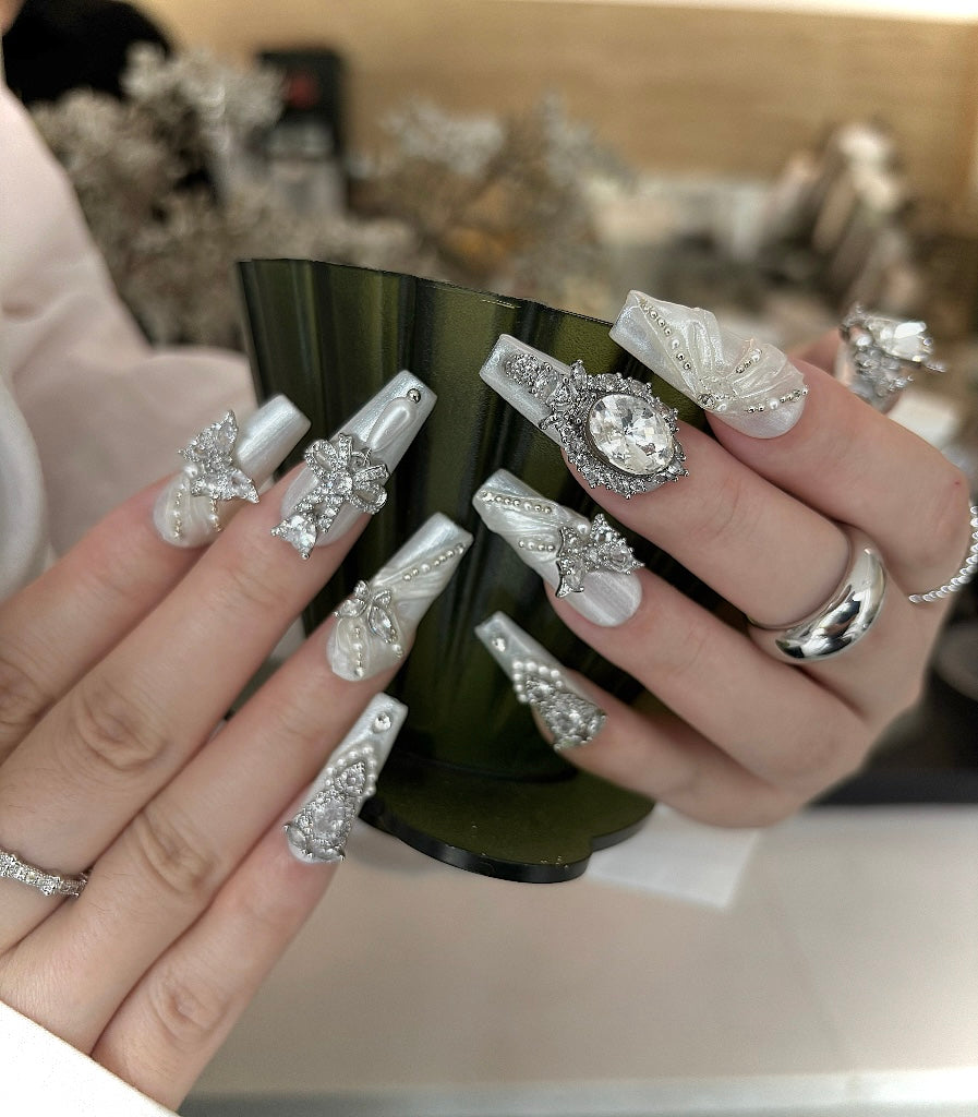 Hand with ornate nail art holding a bottle, blurred background