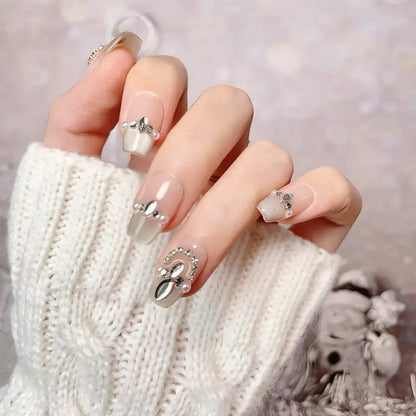 Close-up of a hand with decorative nails wearing a white knitted sweater.