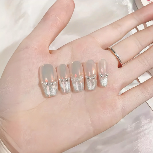 Hand with decorative nails featuring glittery accents on a neutral background