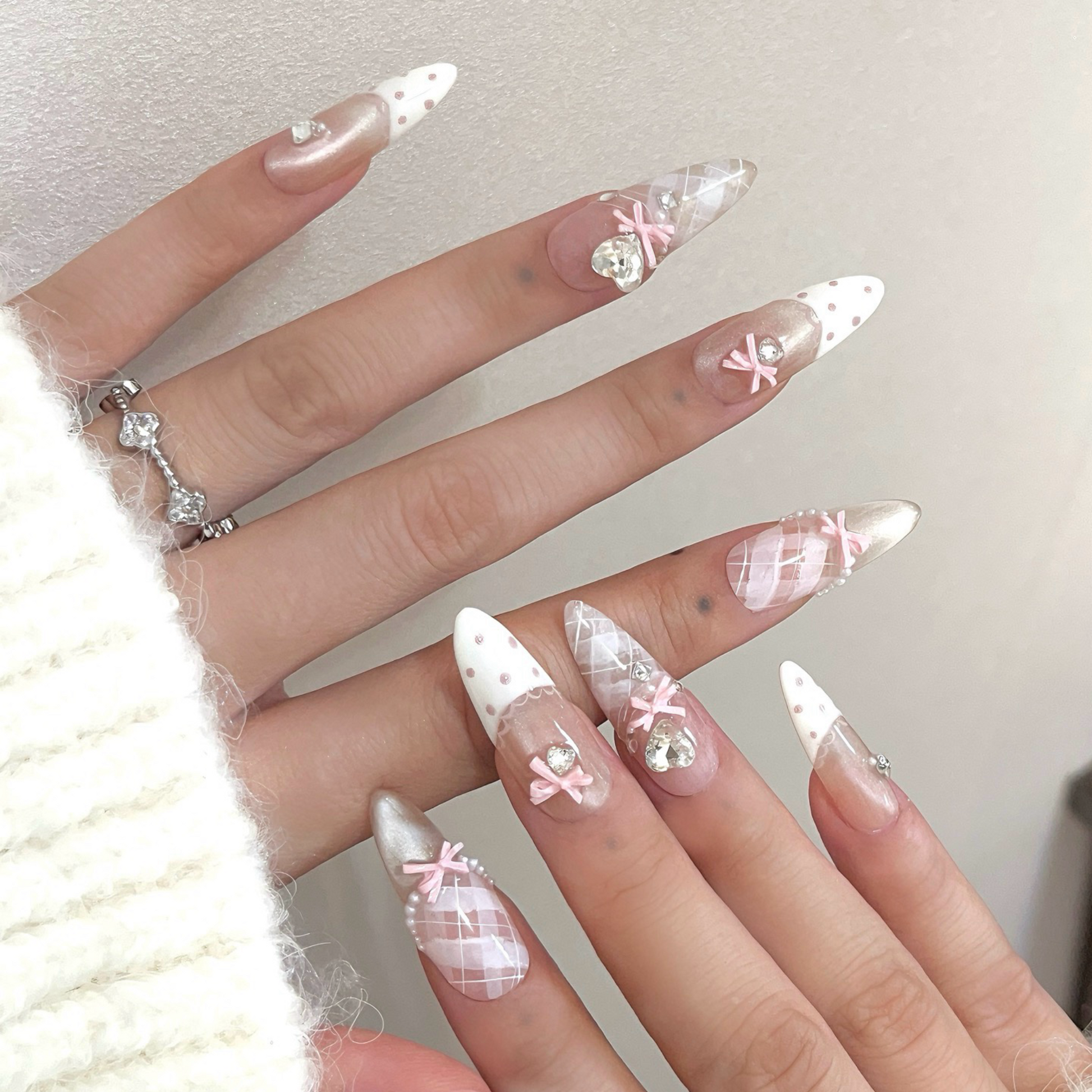 Decorative nails with pink bows and rhinestones on a textured surface with a card reading 'Best wishes for you'.