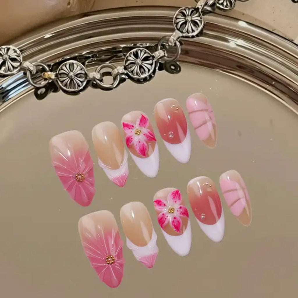 Nail art with pink and white floral designs on a mirror background