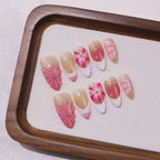 Nail art display with pink and beige flowers on a wooden tray
