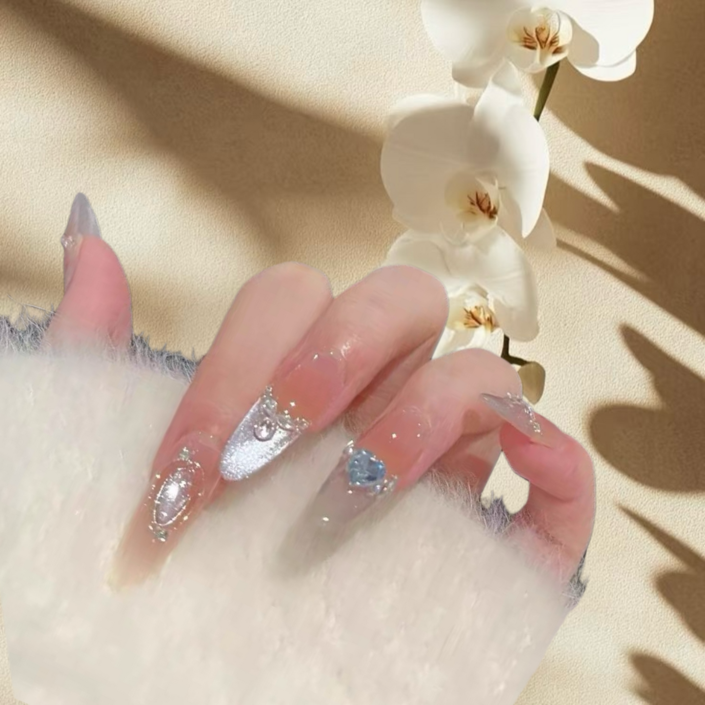 Hand with decorative nails holding a white orchid on a beige background