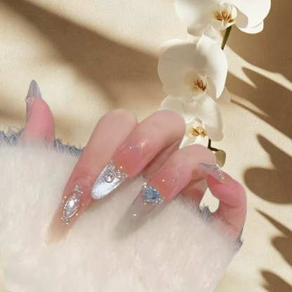 Hand with decorative nails holding a white orchid on a beige background