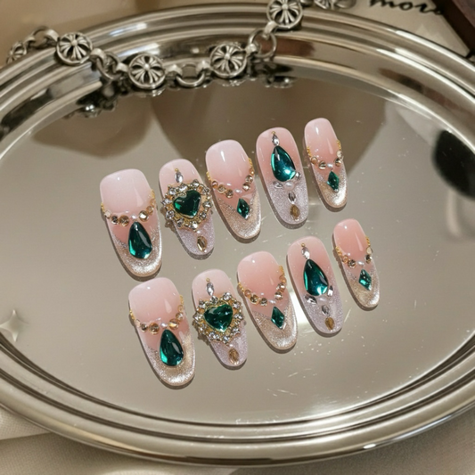 Decorative nails with green and gold elements on a mirror surface