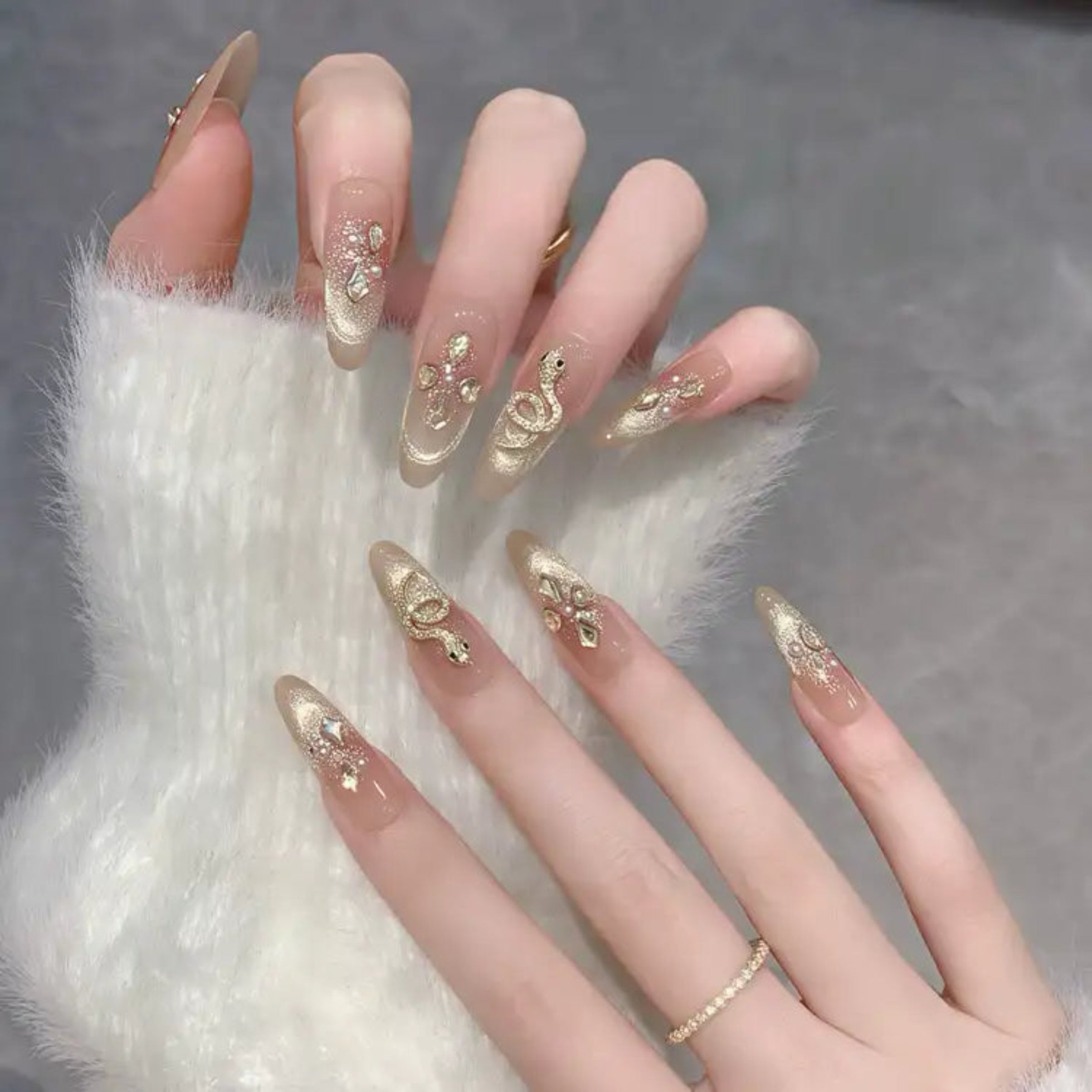 Nails with gold decorative designs on a textured surface