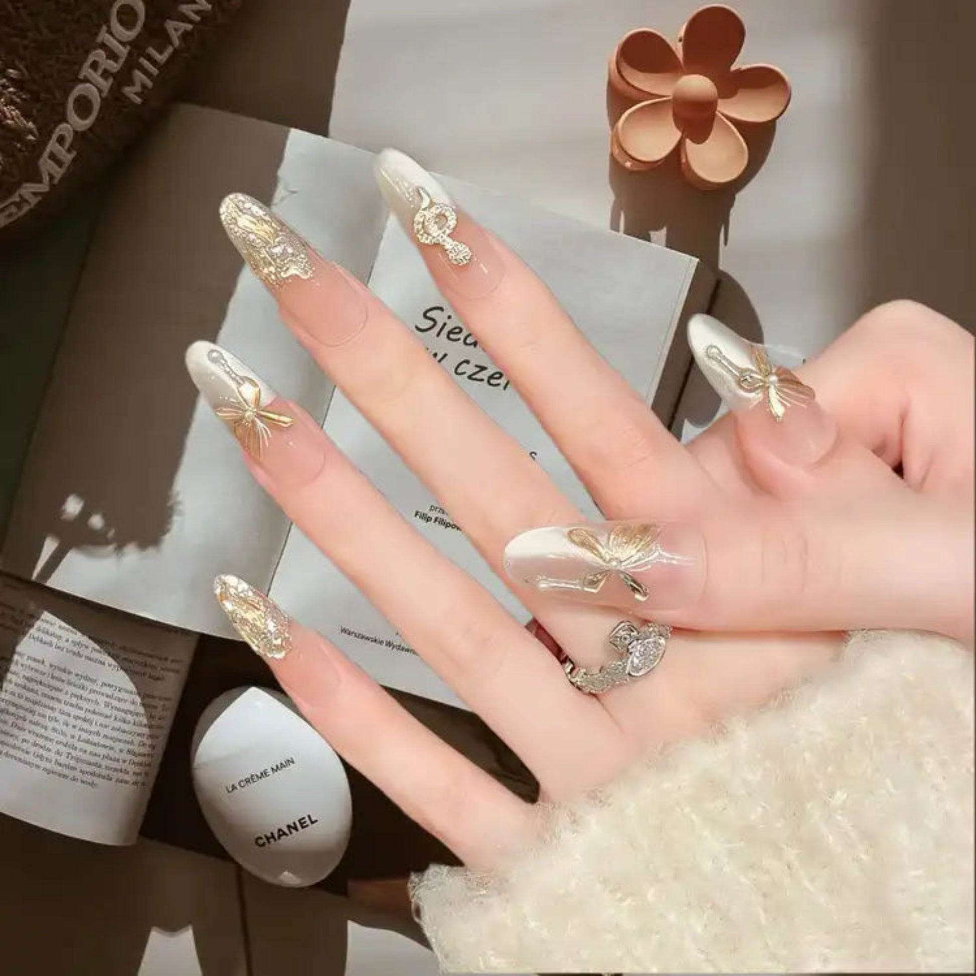 Hand with decorated nails holding a Chanel product, with a blurred background