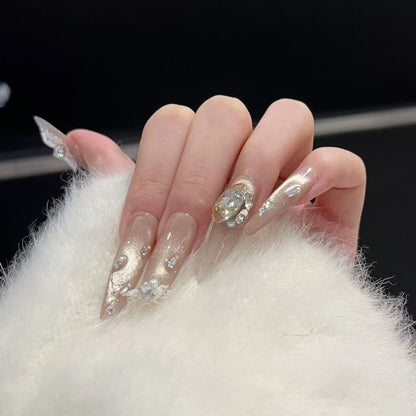 Close-up of a hand with decorative nails featuring crystals on a white fur background.