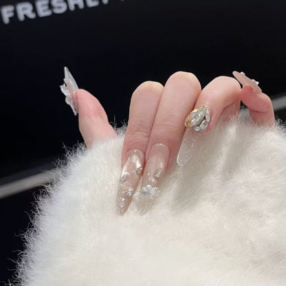 Close-up of a hand with decorative nails wearing a white textured garment.