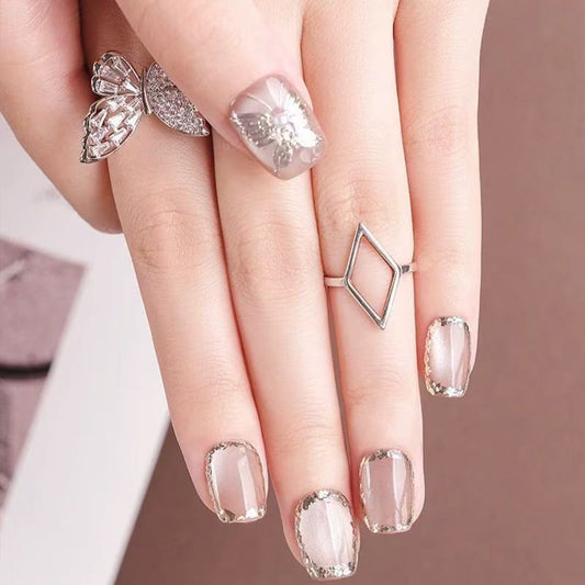 Close-up of a hand with decorative nails and rings on a neutral background
