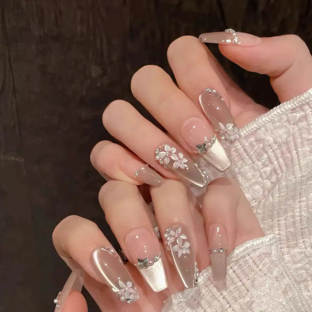 Close-up of hands with clear nail polish and floral designs on a dark background