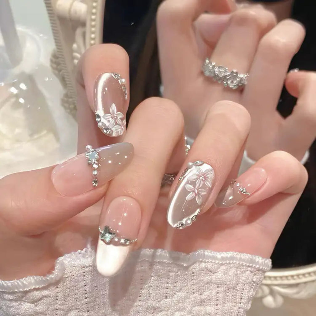Close-up of hands with decorative nail art featuring flowers and rhinestones.