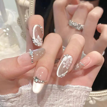 Close-up of hands with decorative nail art featuring flowers and rhinestones.