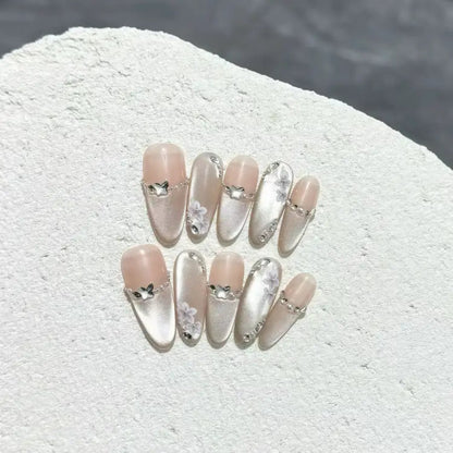 Set of decorative false nails with heart and bow designs on a textured white surface.