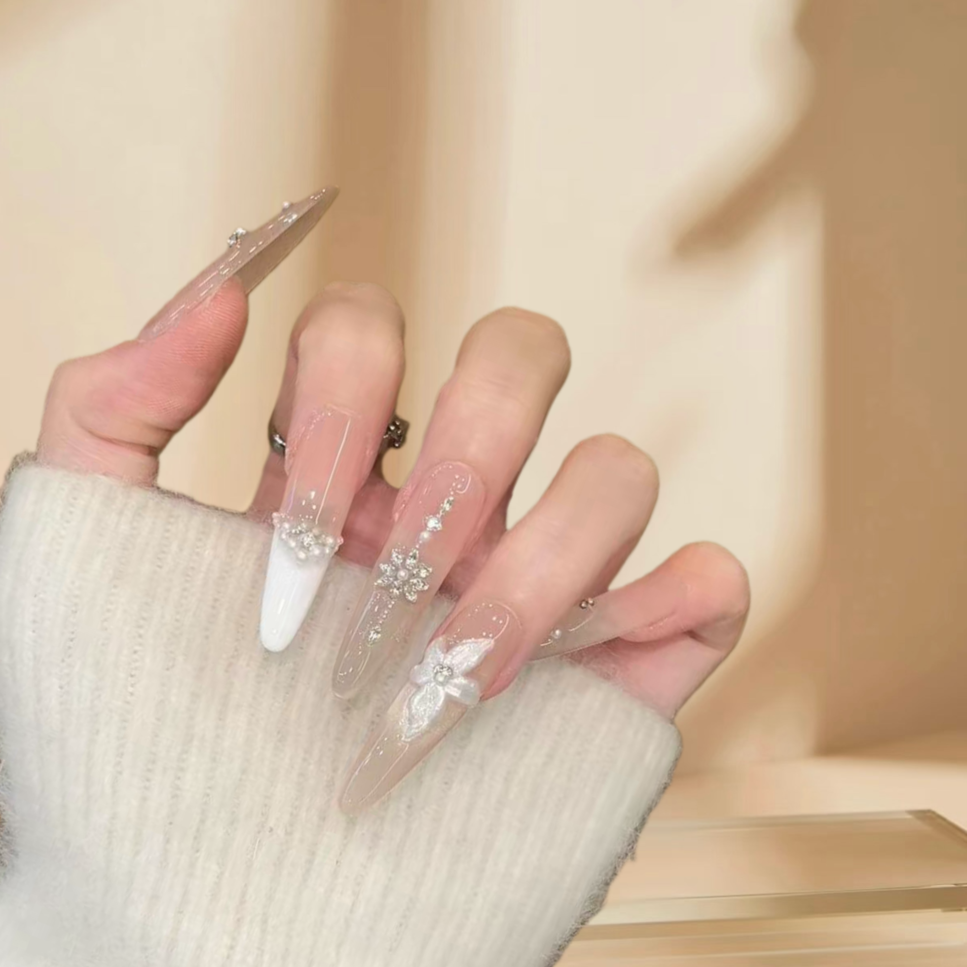 Hand with clear nail polish and decorative elements on a neutral background
