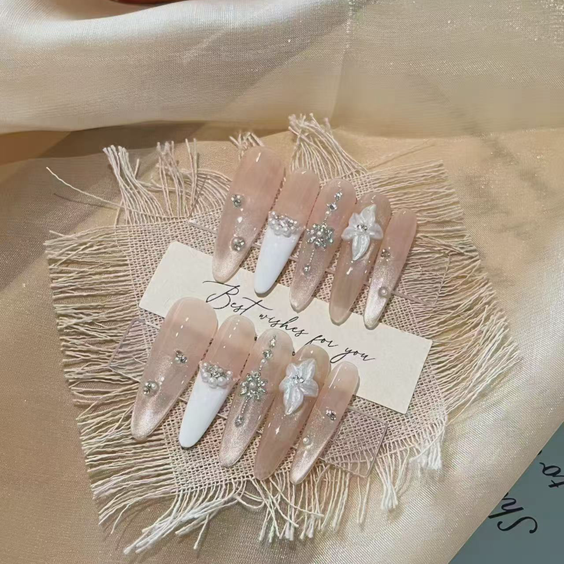 Decorative nails with flowers and pearls on a beige fabric background