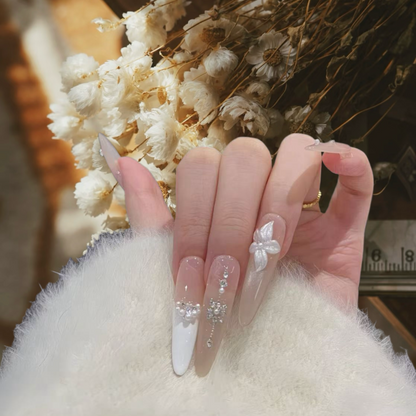 Close-up of a hand with decorative nails in front of white flowers