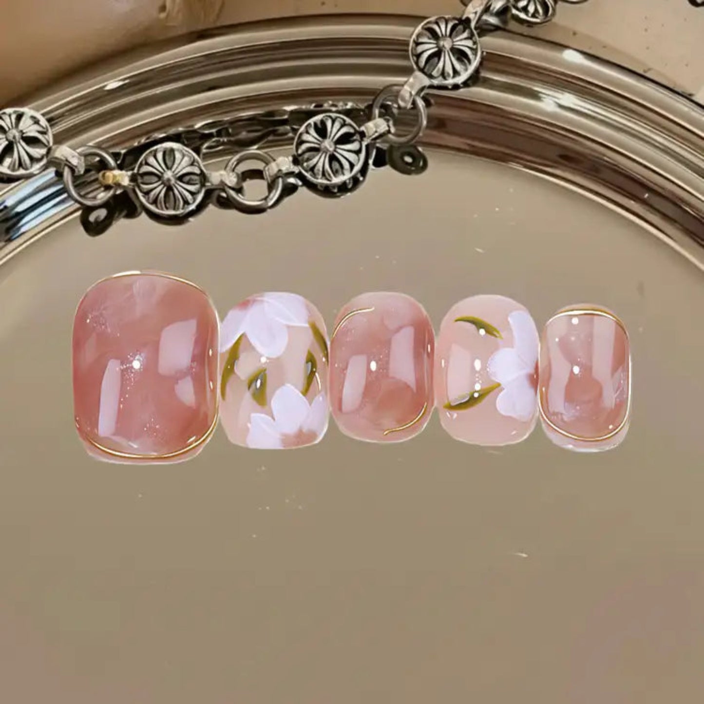 Nail art with floral design on a metallic surface