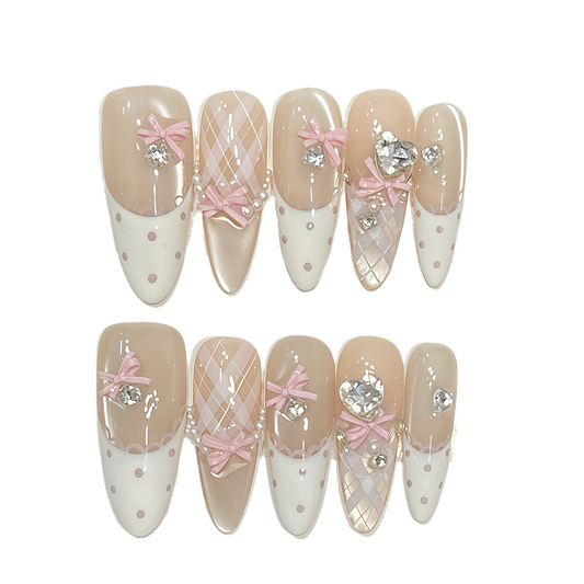 Decorative false nails with pink bows, crystals, and white polka dots on a beige and white background.