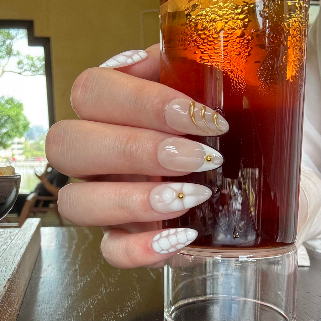 Hand with decorative nails holding a glass of iced tea.