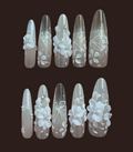 Set of decorative nail extensions with floral and geometric designs on a dark background