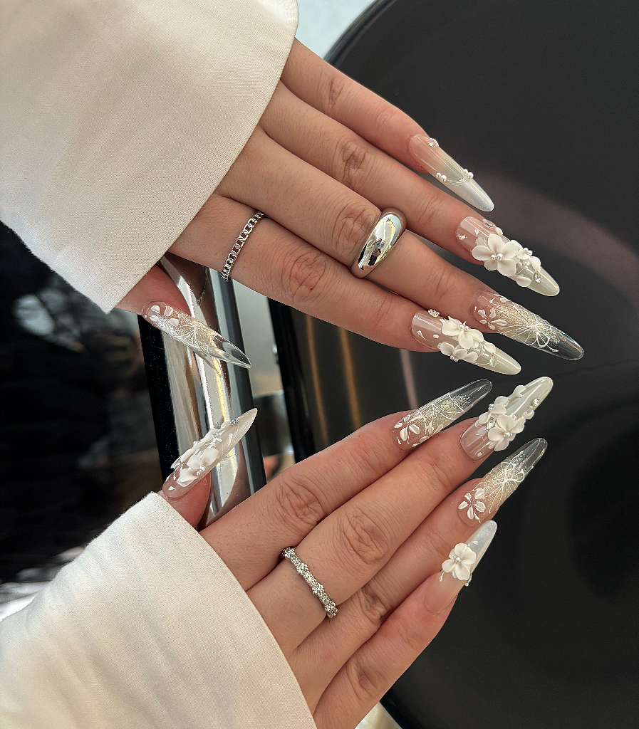 Close-up of hands with decorative nail art and rings.