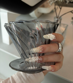 Hand holding a clear glass bowl with decorative nail art