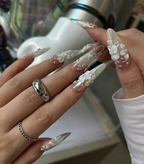 Close-up of hands with long, decorative nails and silver rings.