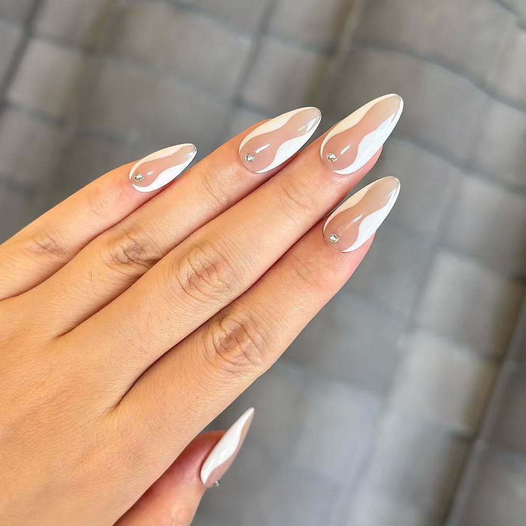 Hand with almond-shaped nails featuring a clear nail polish design on a neutral background